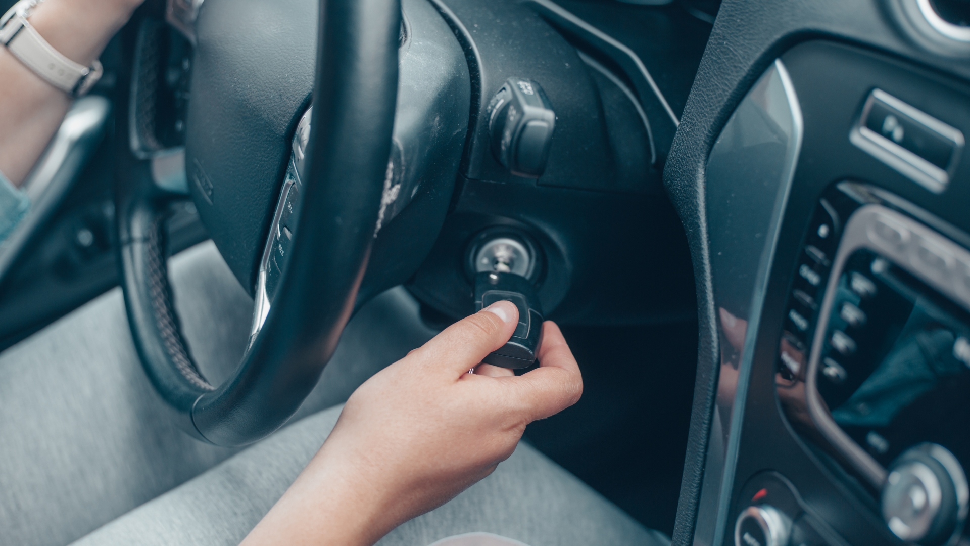 A vehicle owner turns a key in a car ignition, possibly dealing with broken car keys.