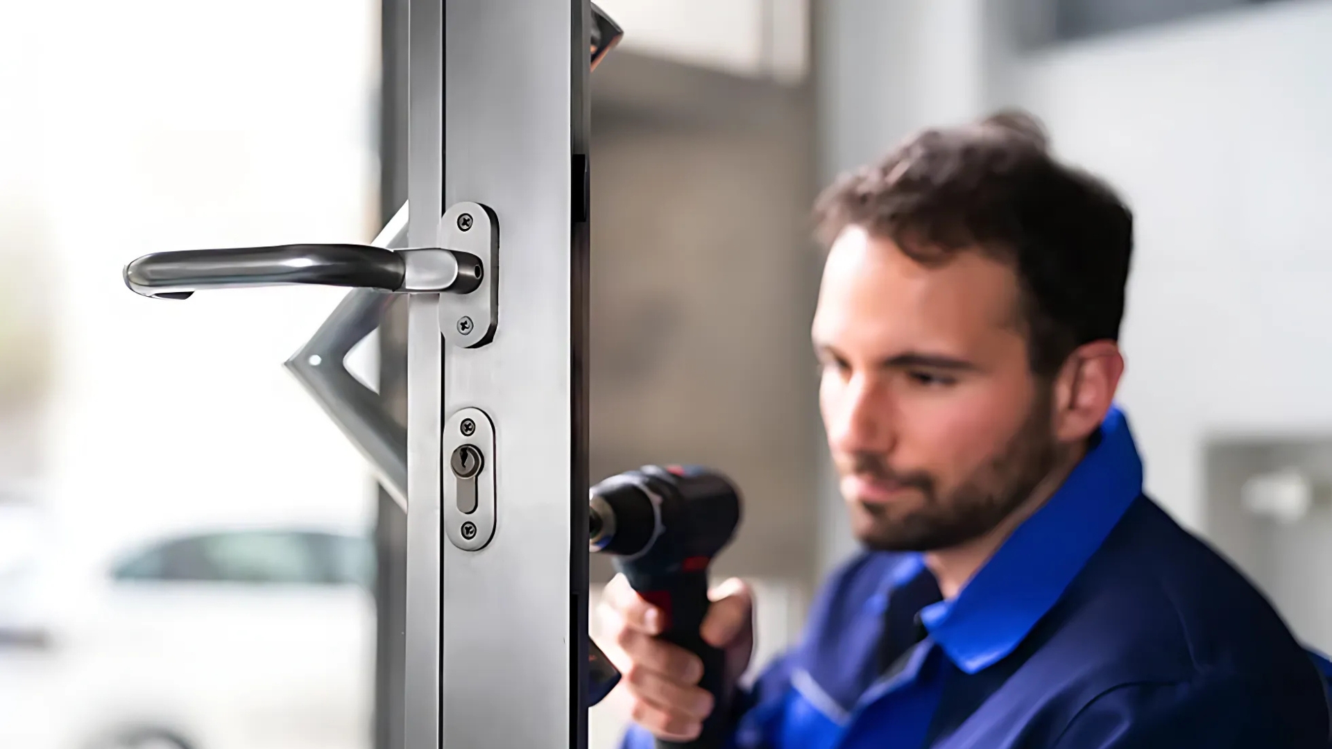 A locksmith is installing a new door lock during a security upgrade.