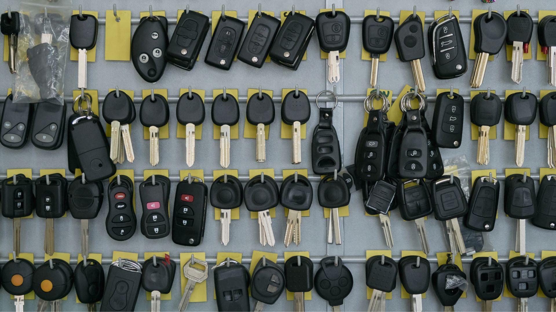 A variety of car key fobs and traditional keys hanging on hooks, ready for programming and duplication