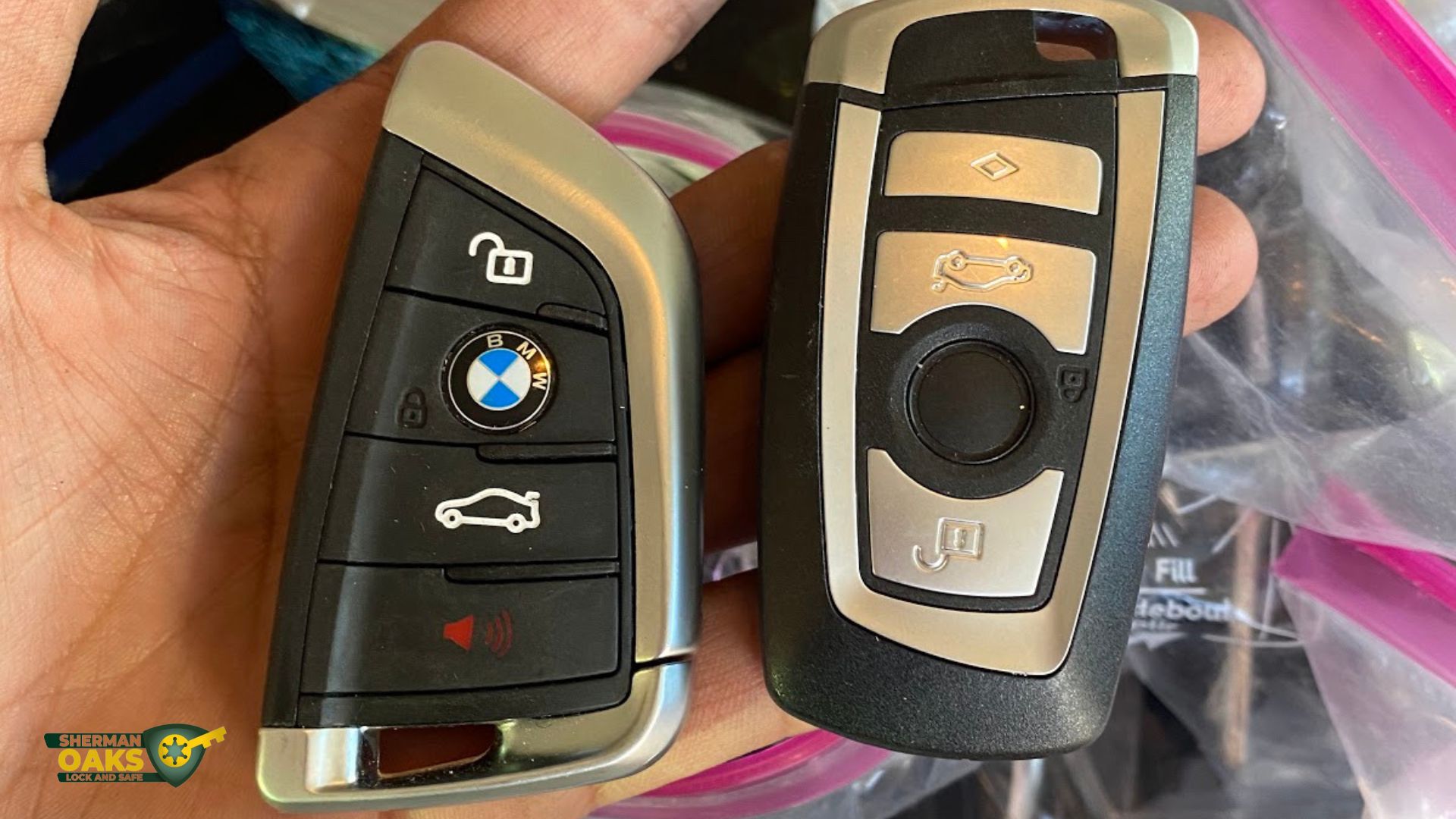 Two car key fobs held in hand, illustrating common issues when a remote is not working, Sherman Oaks Lock & Safe branding visible