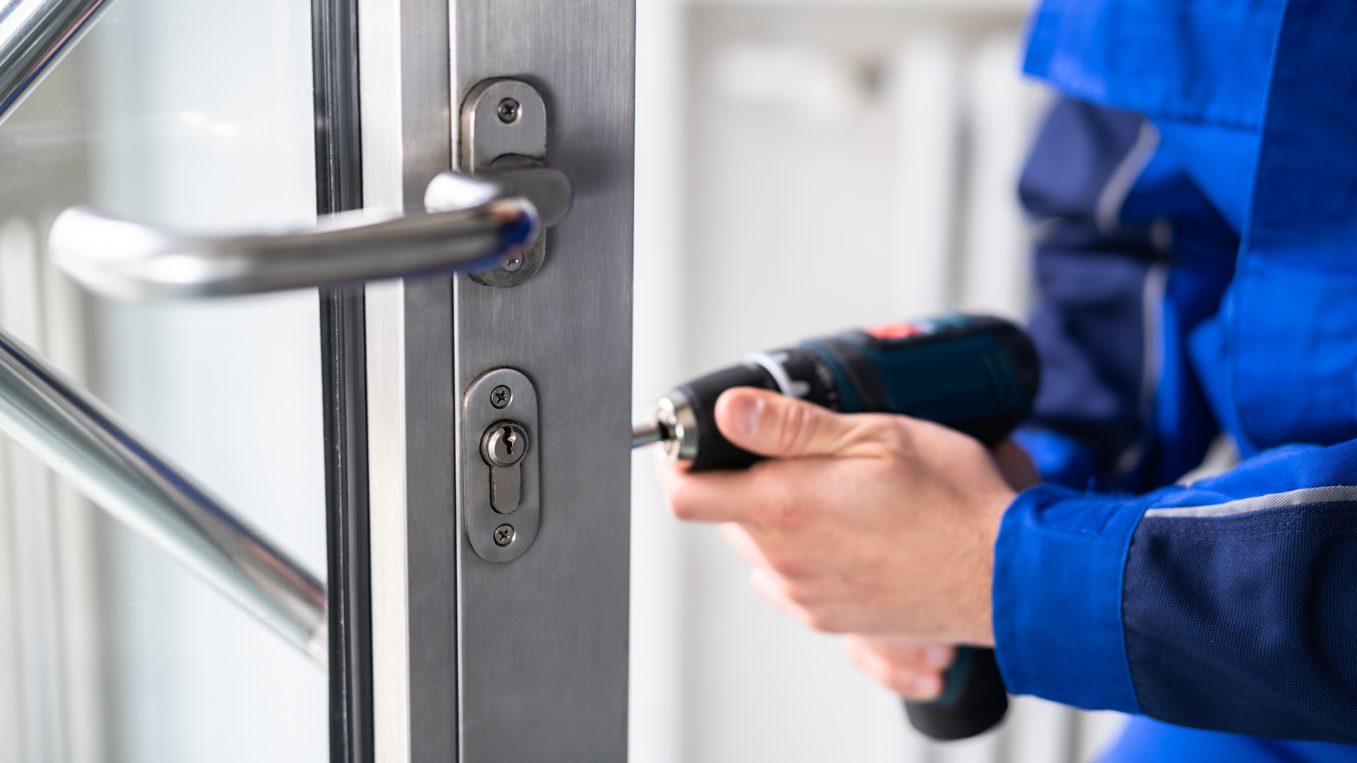Commercial locksmith services technician installing a lock on a glass storefront door to improve business security.