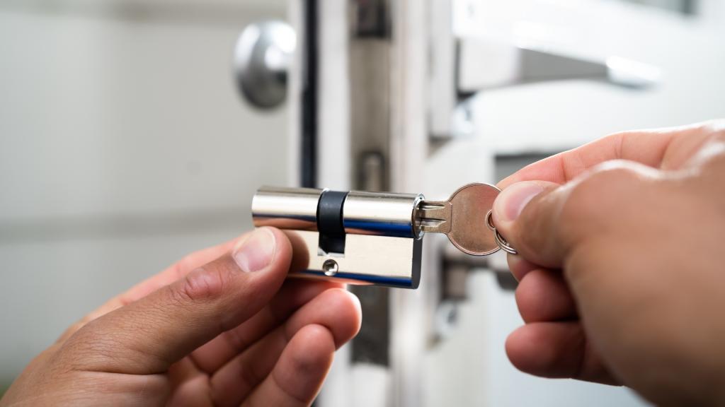 Locksmith in Sherman Oaks holding a door lock cylinder and key for rental turnover locks between tenants